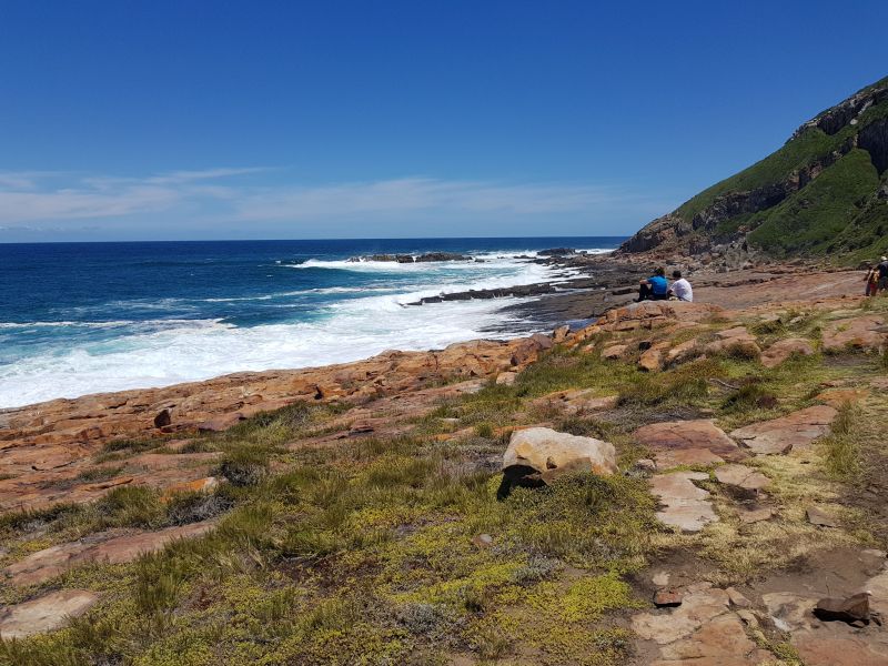 The deep blue sea charges up the rocky shore, crashing into foamy white waves 深蓝海水在岩石冲成层层气泡