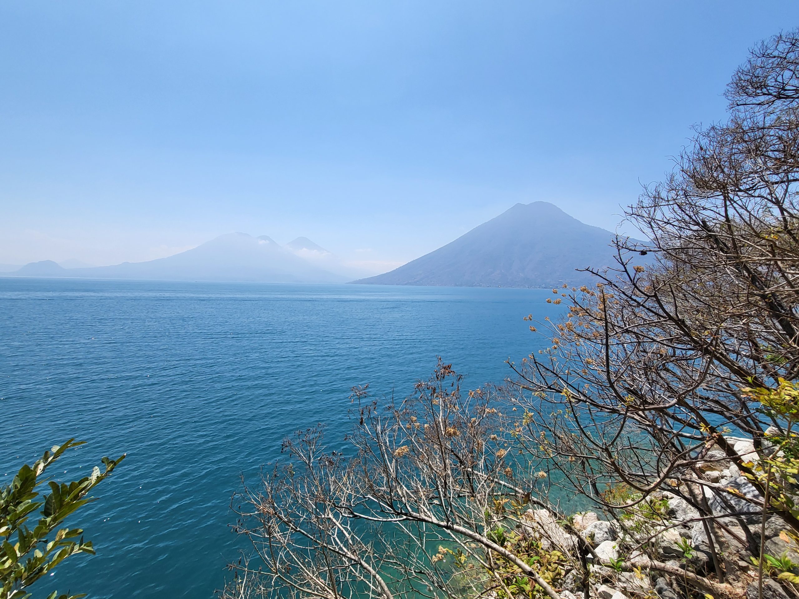 The quiet volcanoes and calm lake painted in serene blue, from the cliff at San Marcos 