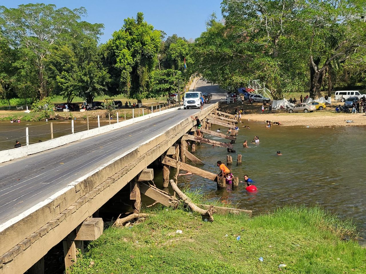 The locals playing in the water under the old wooden bridge over the Macal River