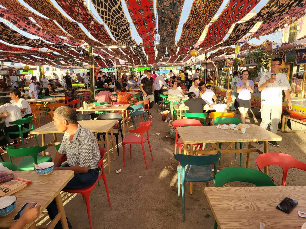 Both Uyghurs and Chinese using chop sticks to sample local treats