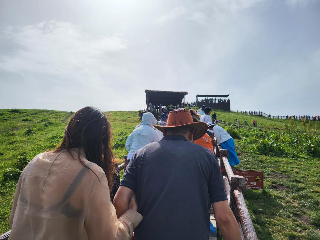 The crowd climbing the slope to a viewpoint on the Nalati Grassland