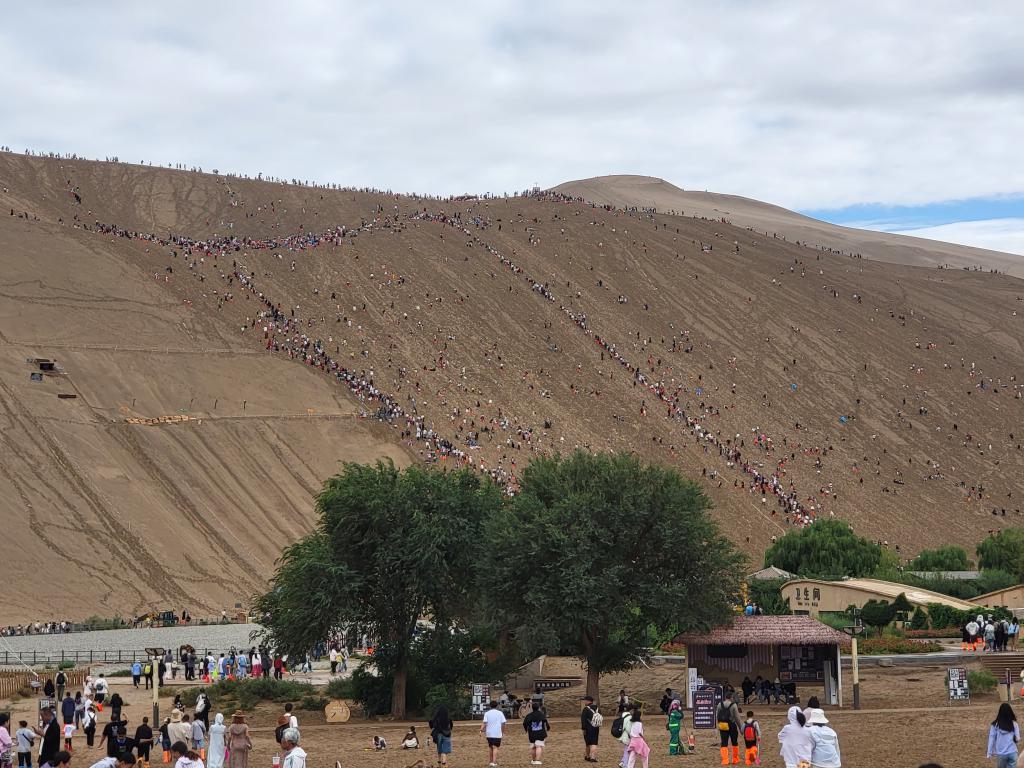 The crowd climbing the dunes at Yueyaquan